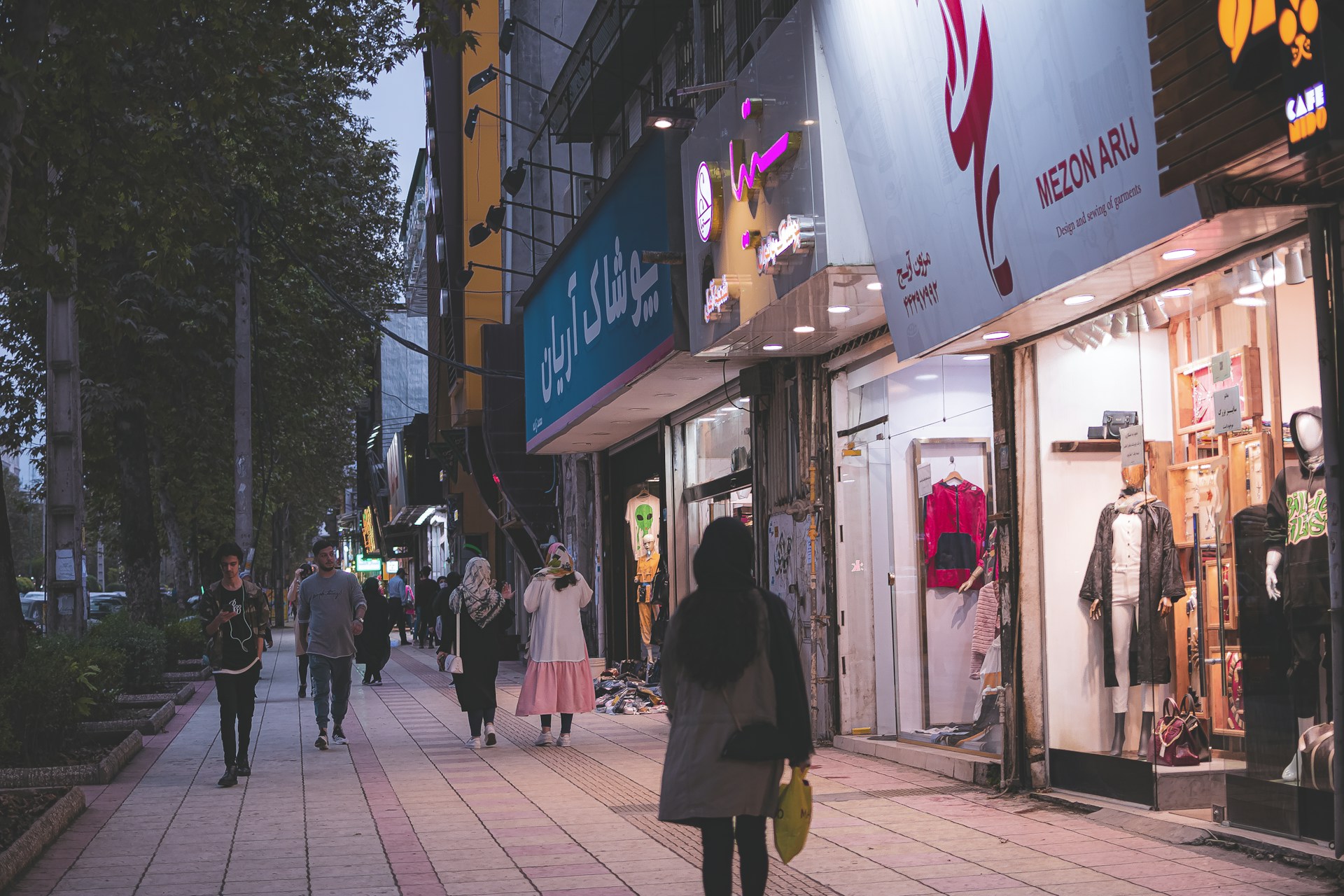 A vibrant urban street scene featuring trendy fashion shoppers carrying stylish bags under bright city lights.