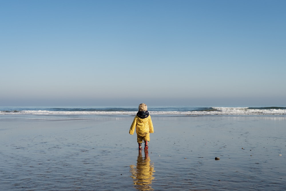 woman in yellow dress walking on beach during daytime