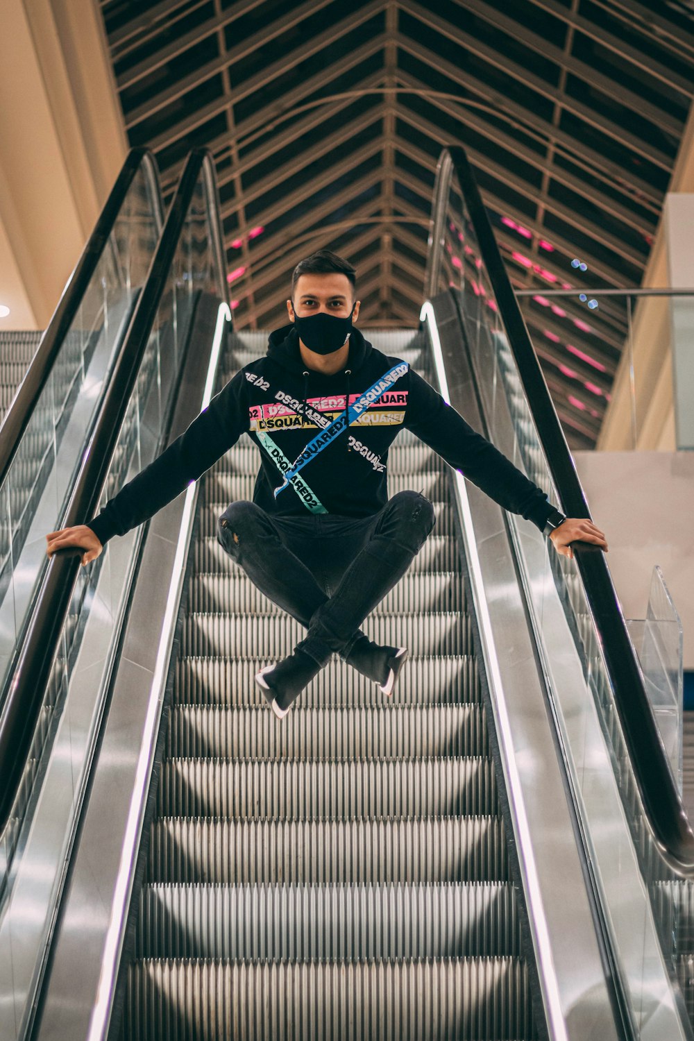 man in black jacket and black pants sitting on escalator