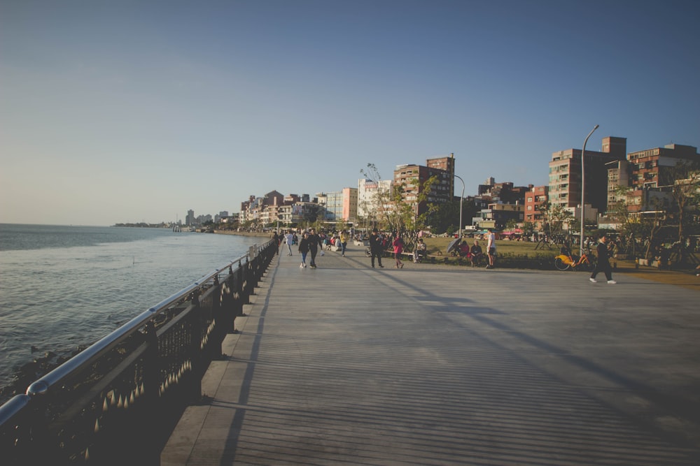 people walking on sidewalk near body of water during daytime