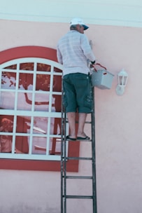 woman in white and blue striped long sleeve shirt and blue denim jeans standing on ladder