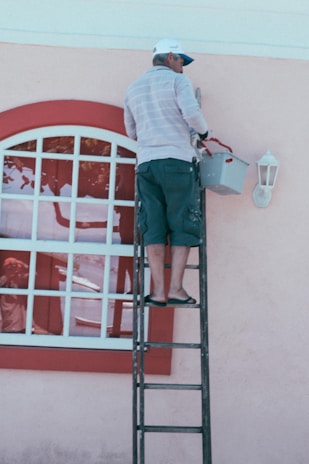 woman in white and blue striped long sleeve shirt and blue denim jeans standing on ladder