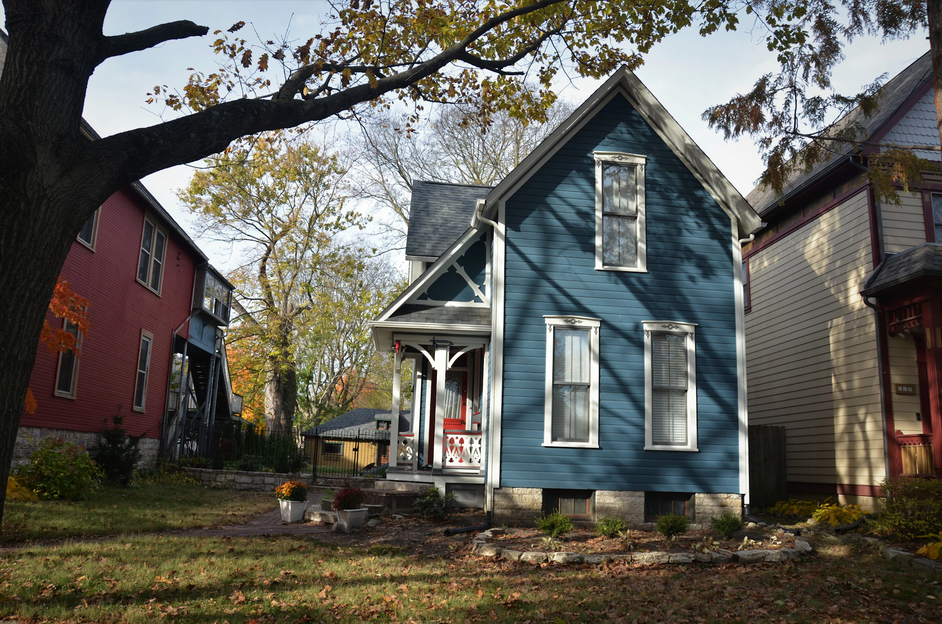 A freshly painted classic New England clapboard home in Saint Johnsbury, with crisp white trim and a deep blue exterior shining under a clear sky.