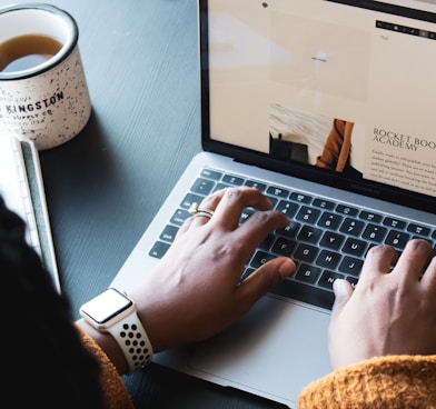 person using macbook pro on black table