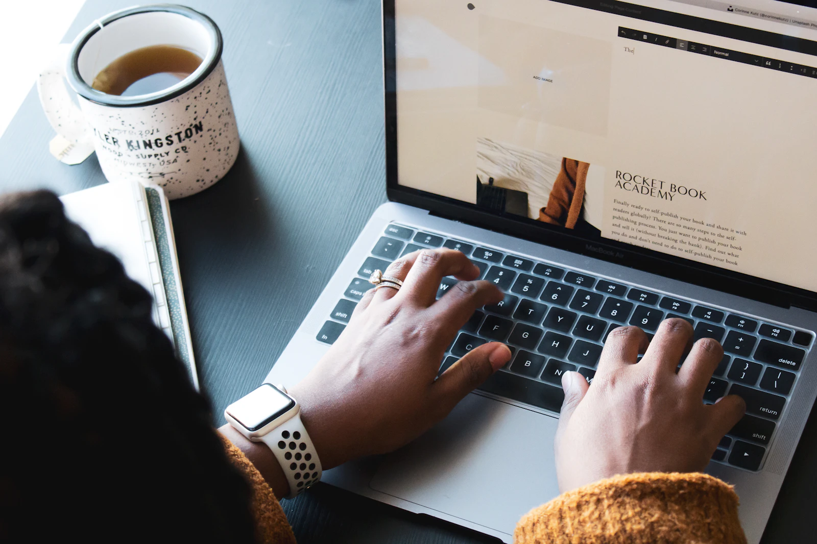 Freelancer typing on a MacBook reviewing financial dashboards on a dark desk