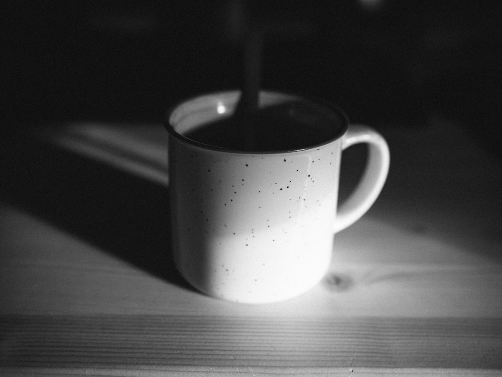grayscale photo of a mug with a lighted candle