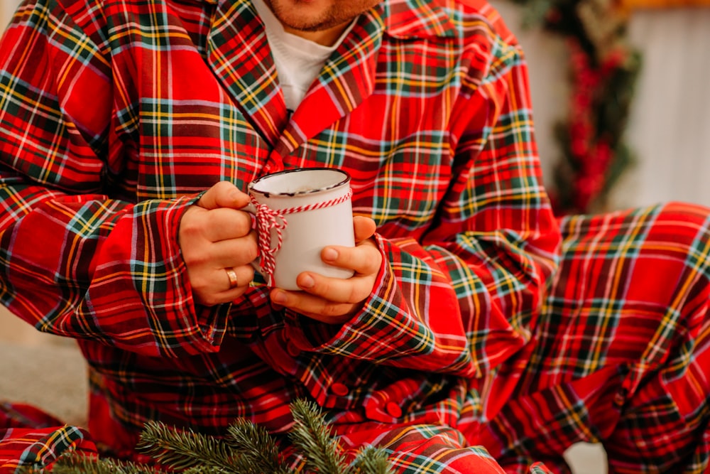 hombre con camisa de vestir a cuadros rojos y negros sosteniendo una taza de cerámica blanca