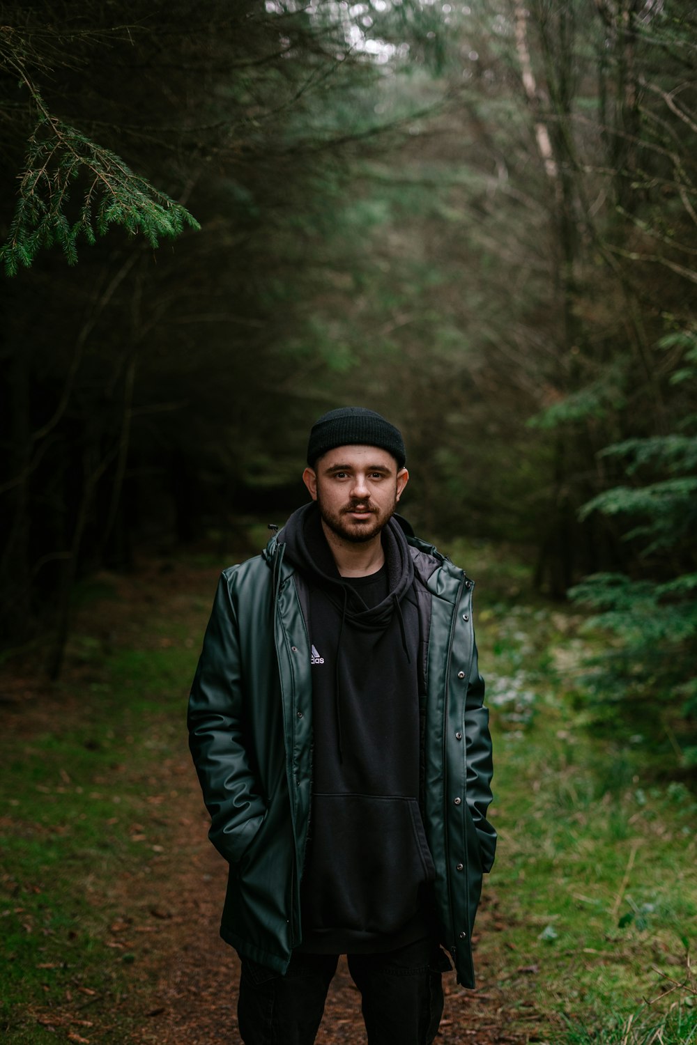 man in black leather jacket standing in forest