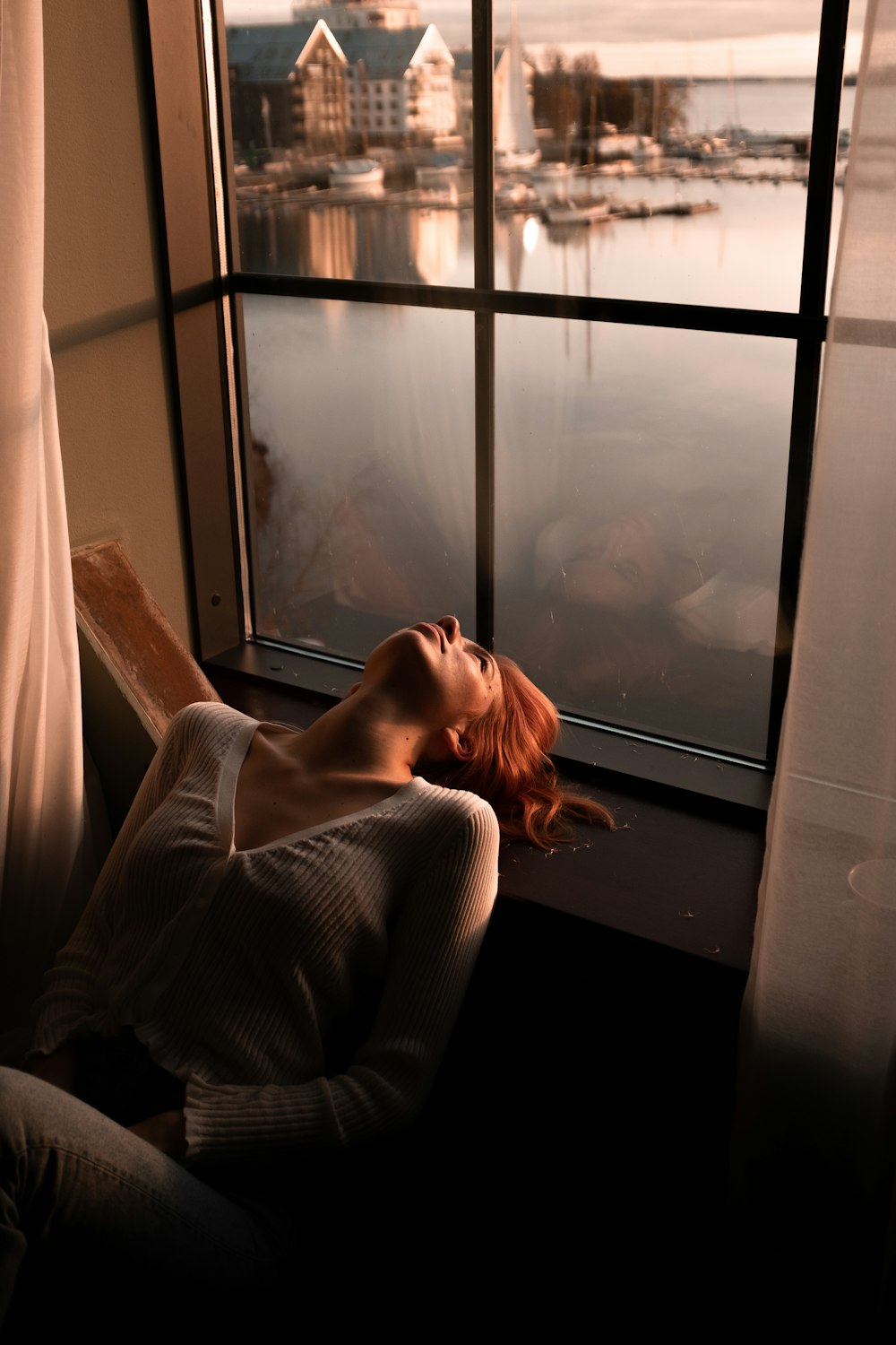 woman in gray sweater sitting beside window