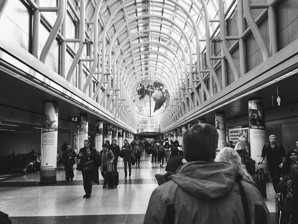 people walking inside building in grayscale photography