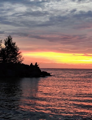 A sunset silhouette of two anglers casting lines side by side.