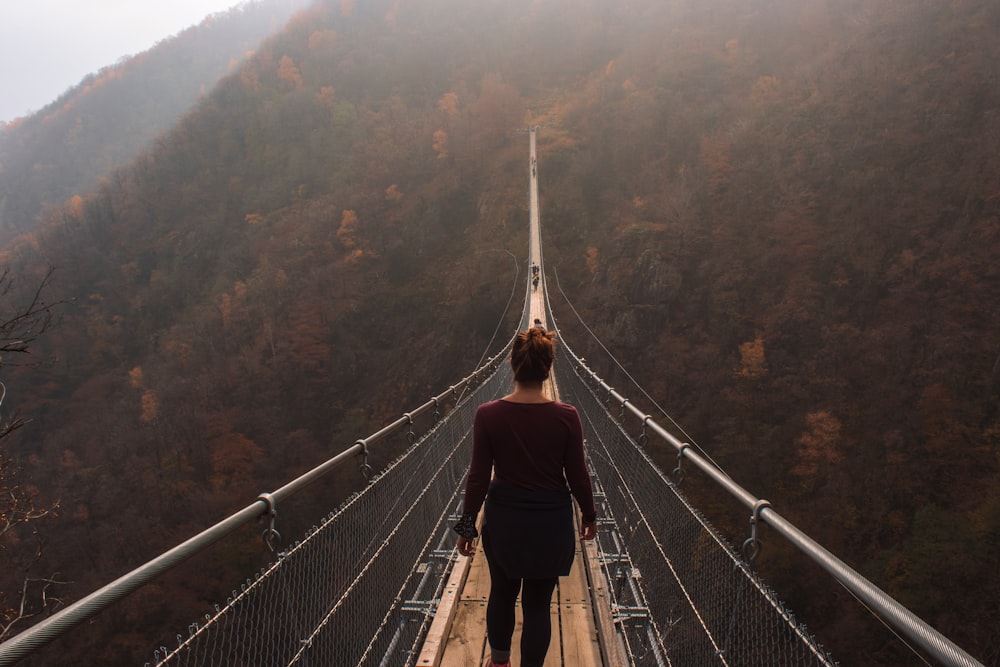 woman in red jacket standing on hanging bridge during daytime