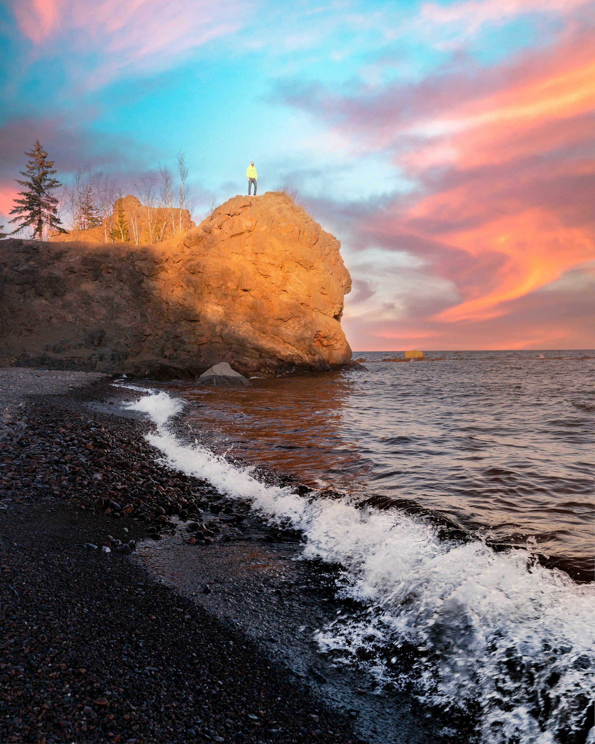 white lighthouse on brown rock formation near body of water during daytime