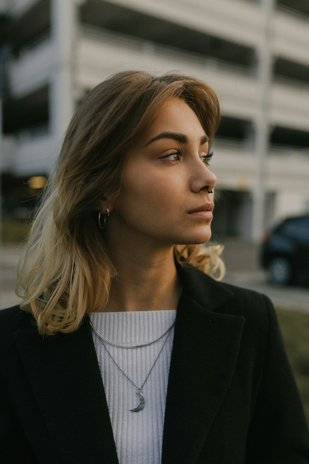 woman in black blazer standing near cars during daytime