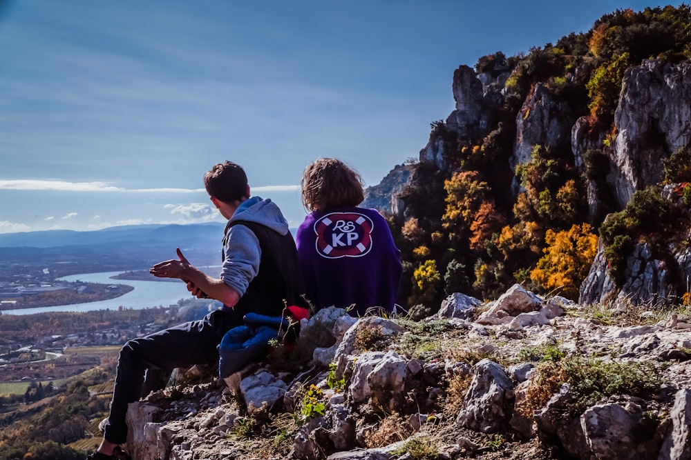 man in black jacket sitting on rock during daytime