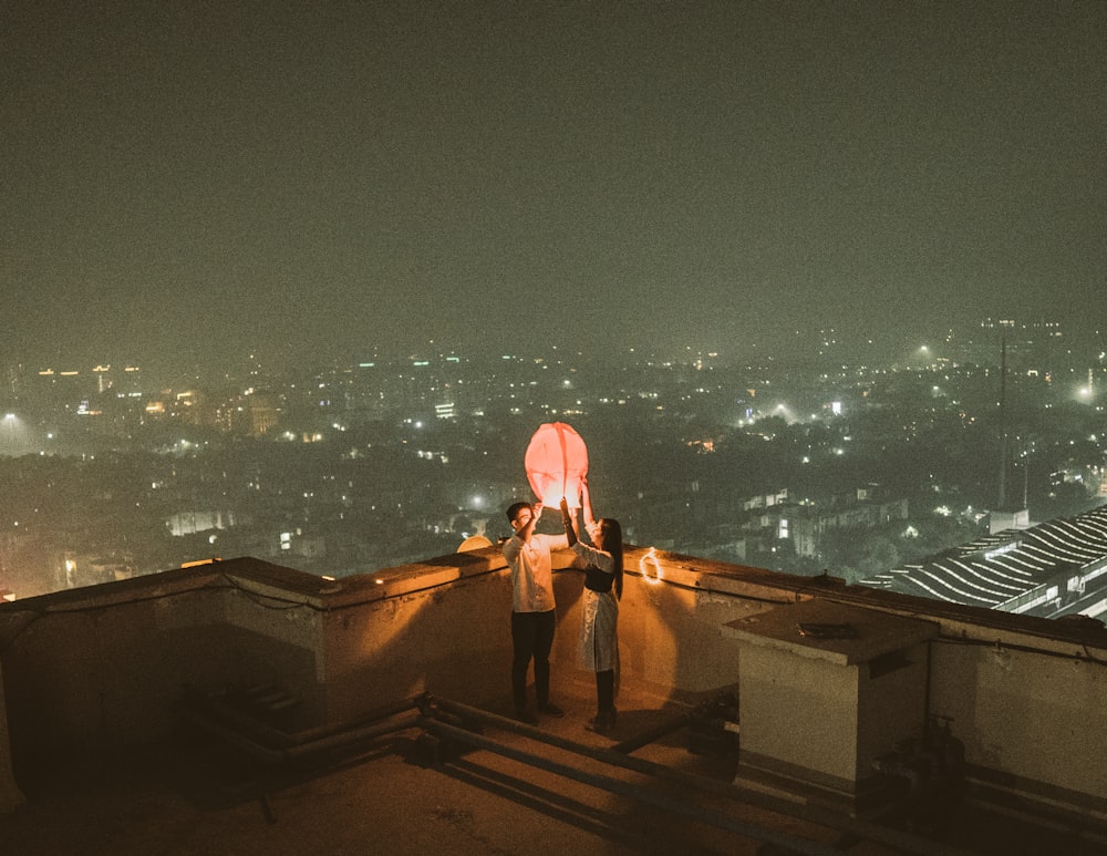 2 women standing on brown wooden dock during night time