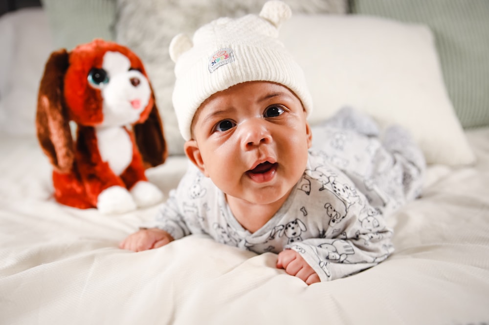 baby in white and gray long sleeve shirt lying on bed