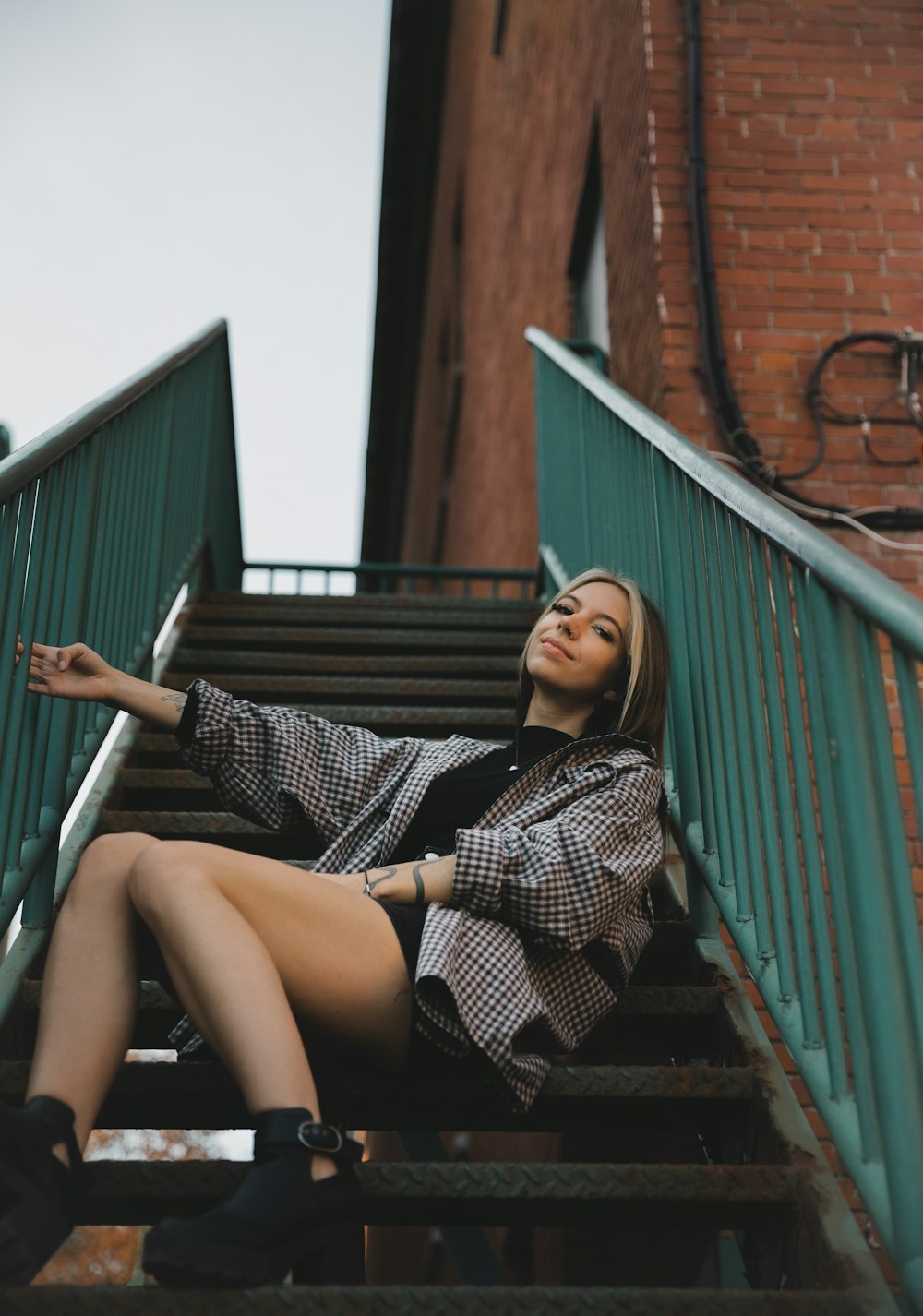 woman in black and white checkered dress sitting on stairs