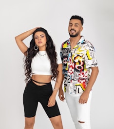 woman in white crop top and black shorts beside man in blue yellow and red floral