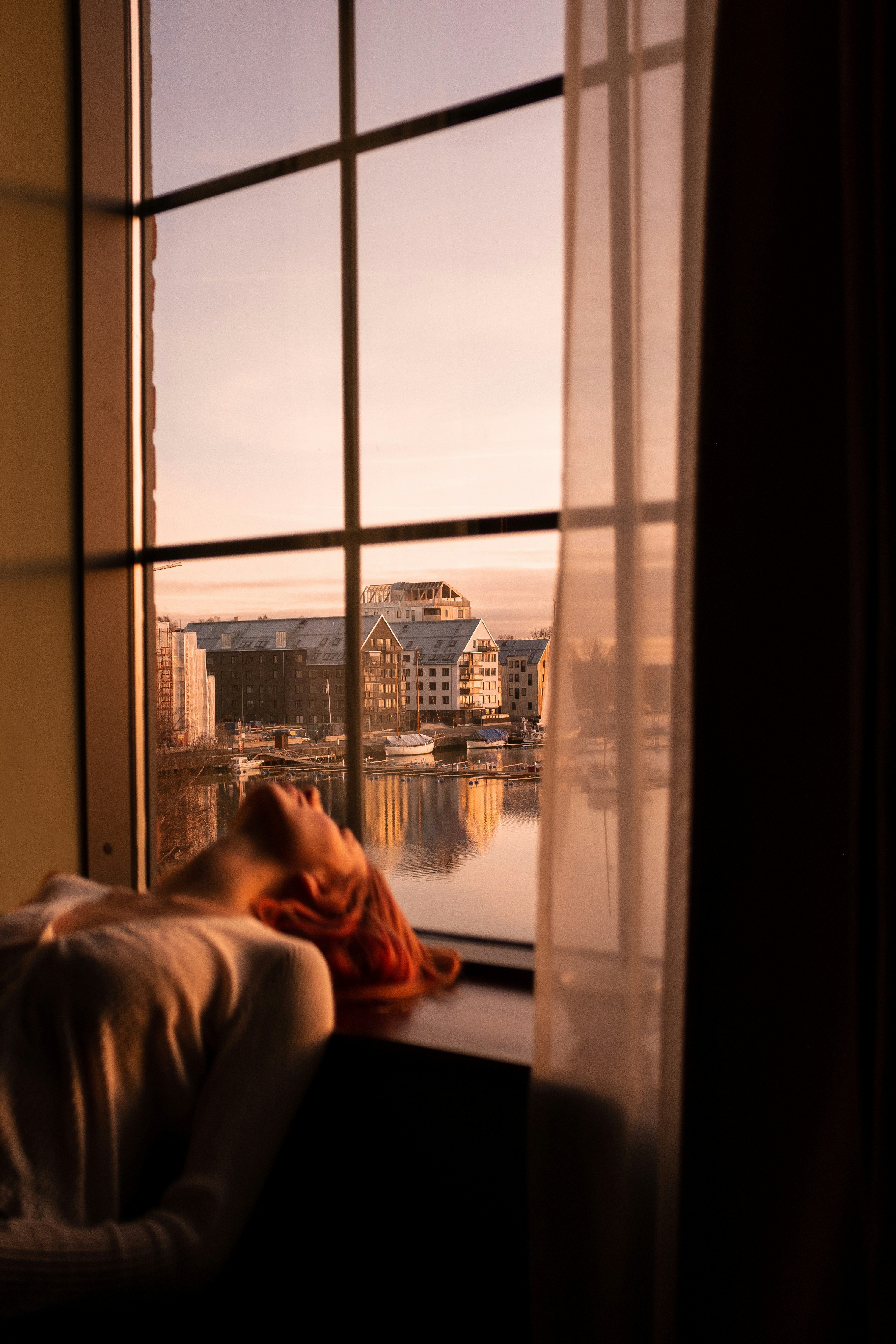 person in white shirt sitting on chair near window