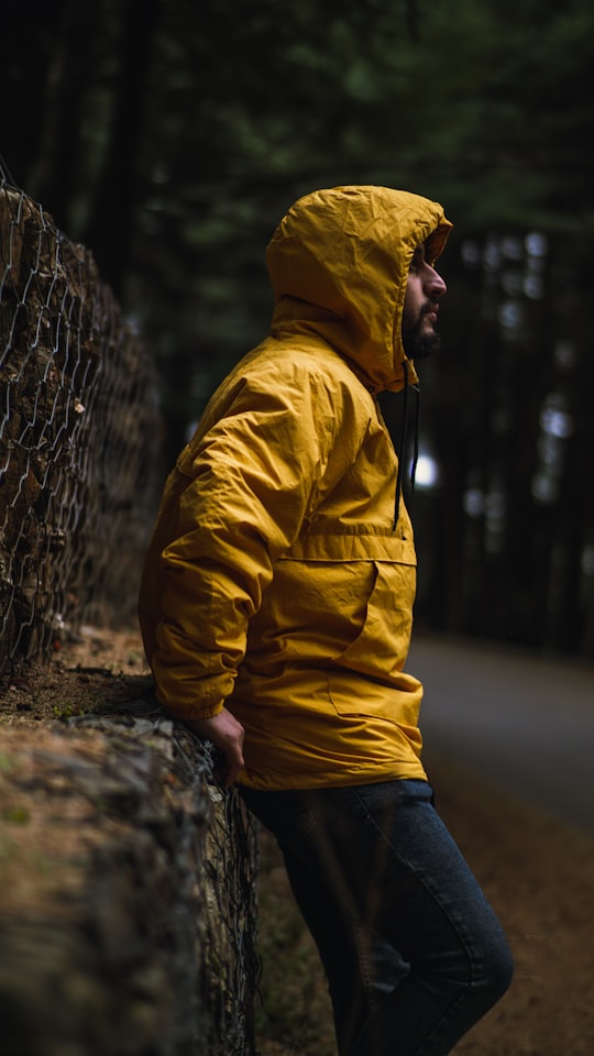 man in yellow hoodie leaning on gray chain link fence in Chrea Algeria