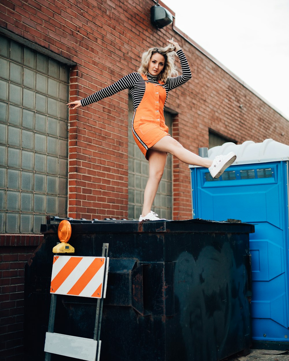 woman in orange dress standing on blue plastic container