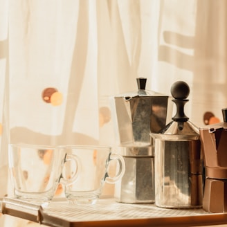 stainless steel pitcher beside clear drinking glass on table