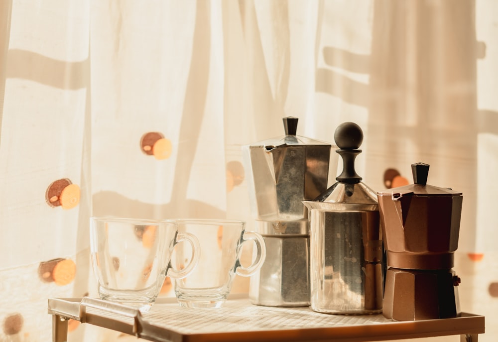 stainless steel pitcher beside clear drinking glass on table