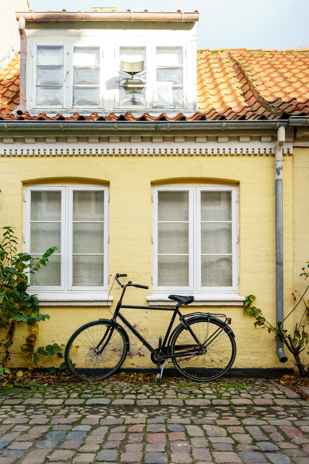 bicicleta preta estacionada ao lado da casa pintada de amarelo