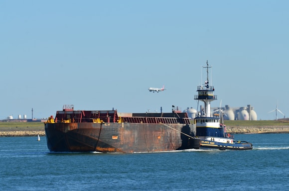 black and red cargo ship on sea under blue sky during daytime