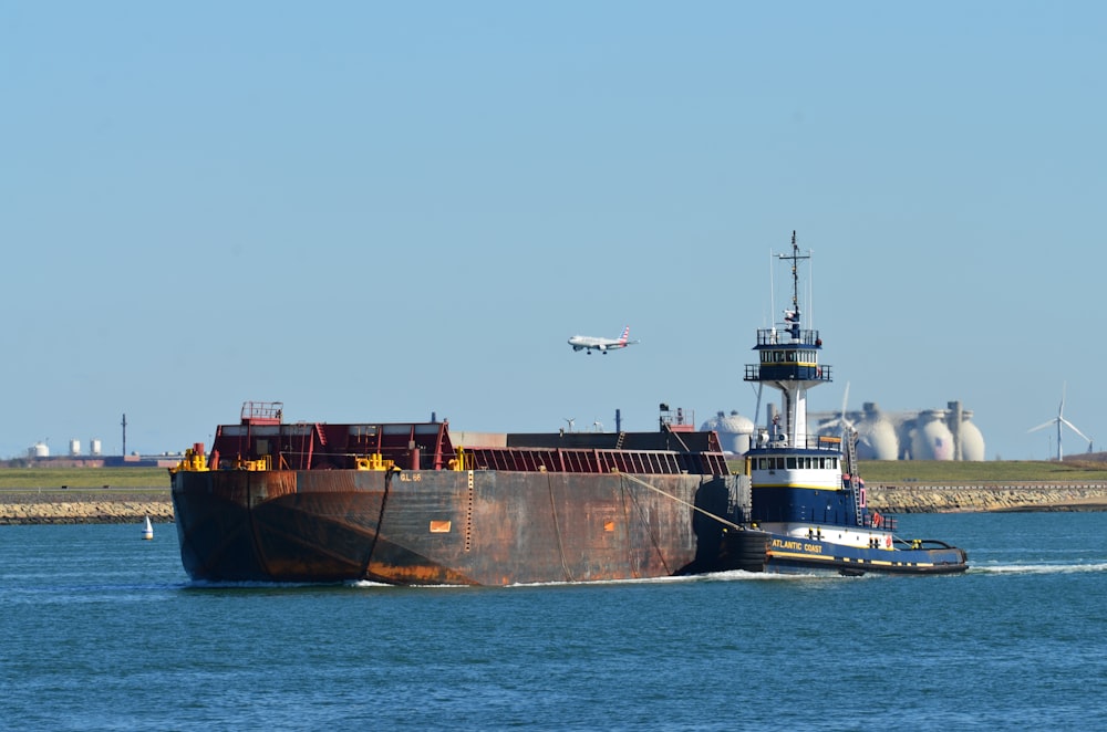 black and red cargo ship on sea under blue sky during daytime