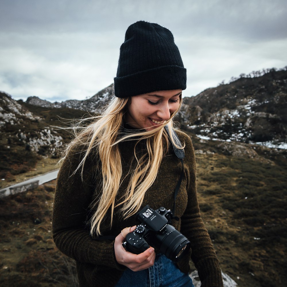 woman in black knit cap holding black dslr camera