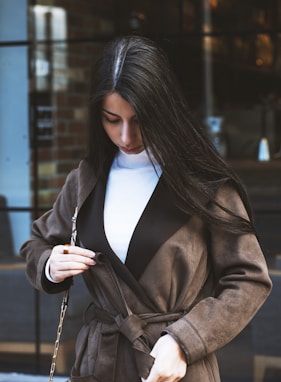 woman in brown coat holding her hair