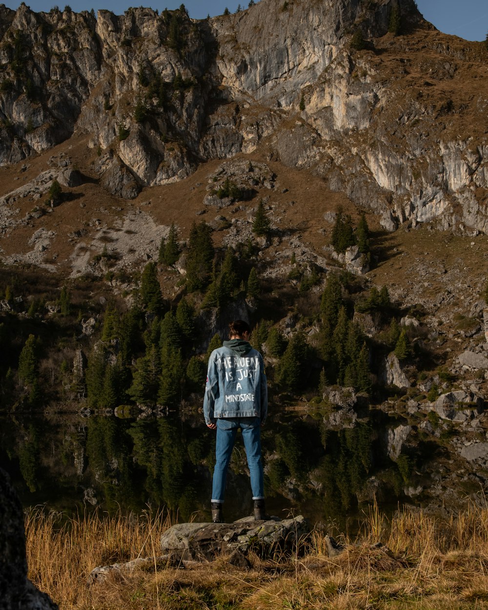 personne en veste bleue debout sur un champ d’herbe brune pendant la journée