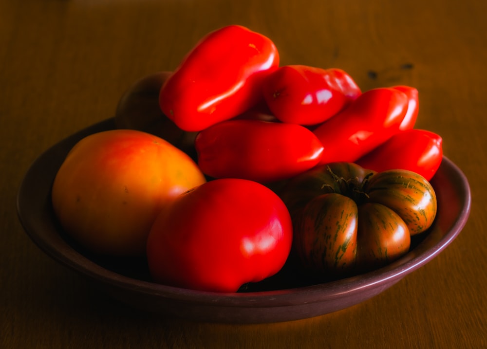 red and yellow round fruits on black ceramic bowl