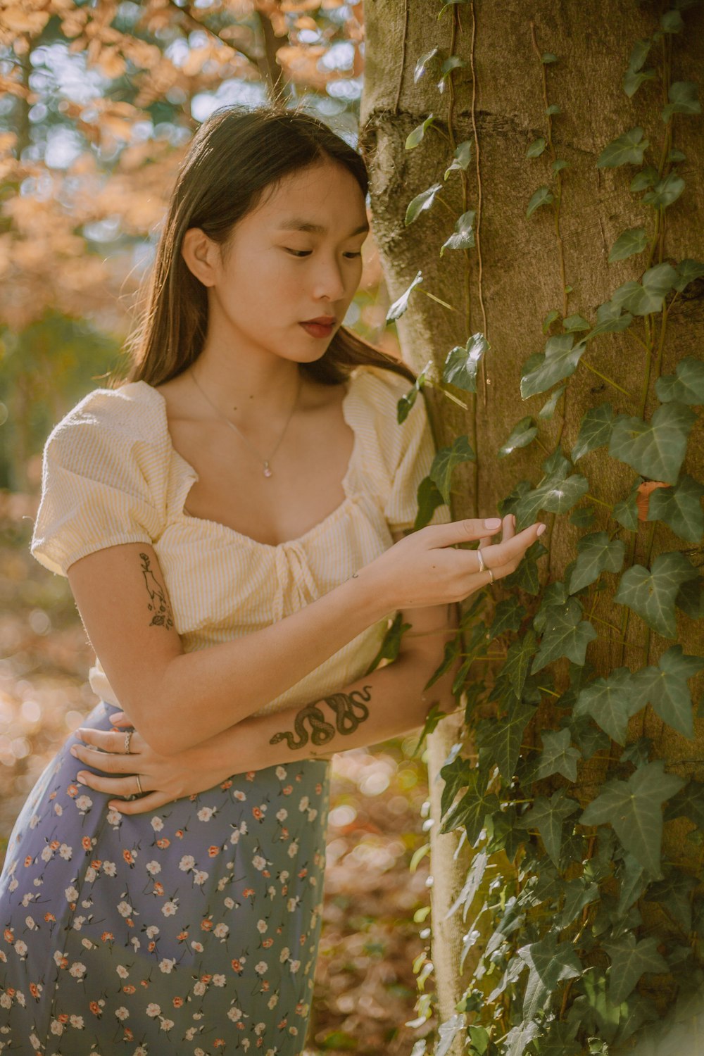 woman in white shirt and blue and white polka dot skirt holding green plant