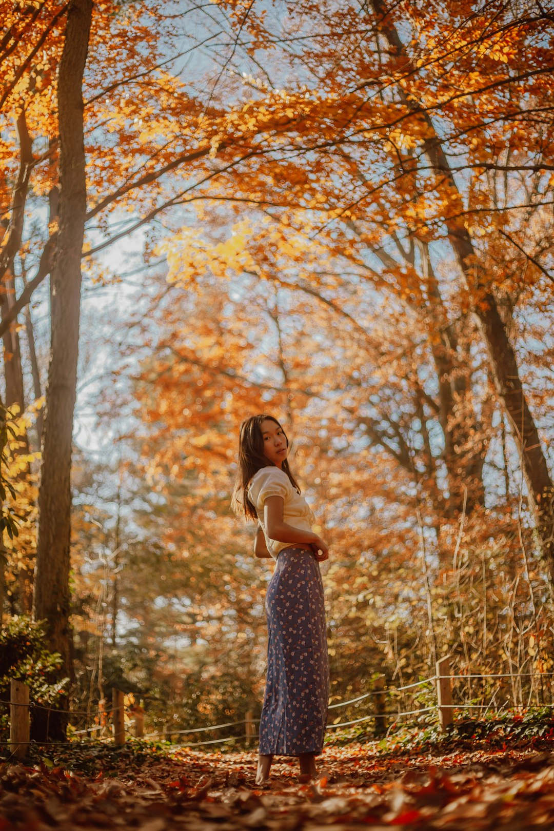 woman in white shirt and black and white floral skirt standing on brown grass field during