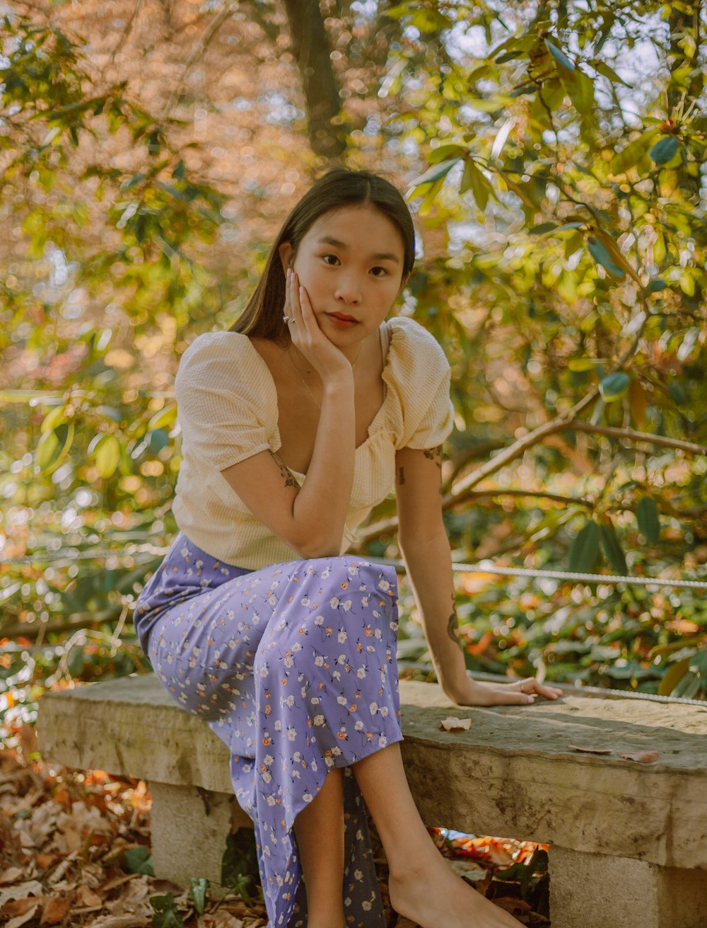woman in yellow shirt and blue and white polka dot skirt sitting on brown wooden bench