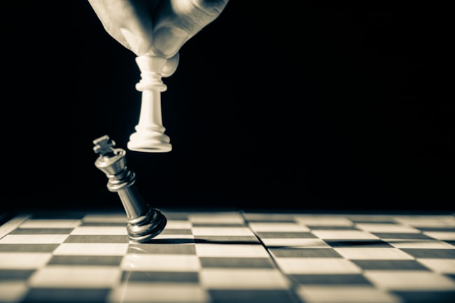 Tabuleiro de xadrez com mão humana dando um xeque-mate