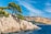green trees on brown rocky mountain beside blue sea under blue sky during daytime
