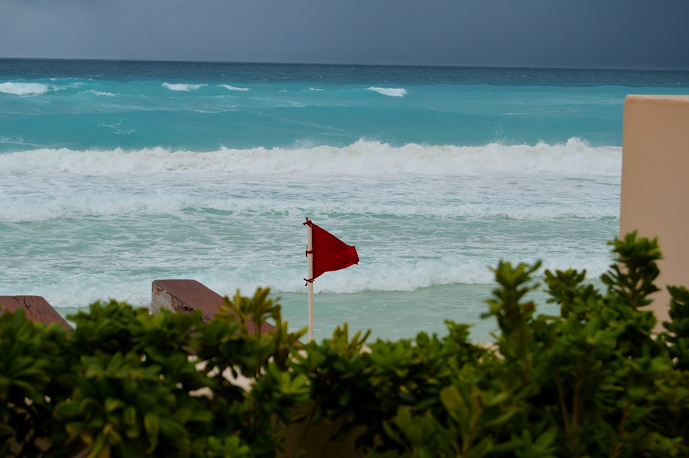 red flag on brown sand near body of water during daytime