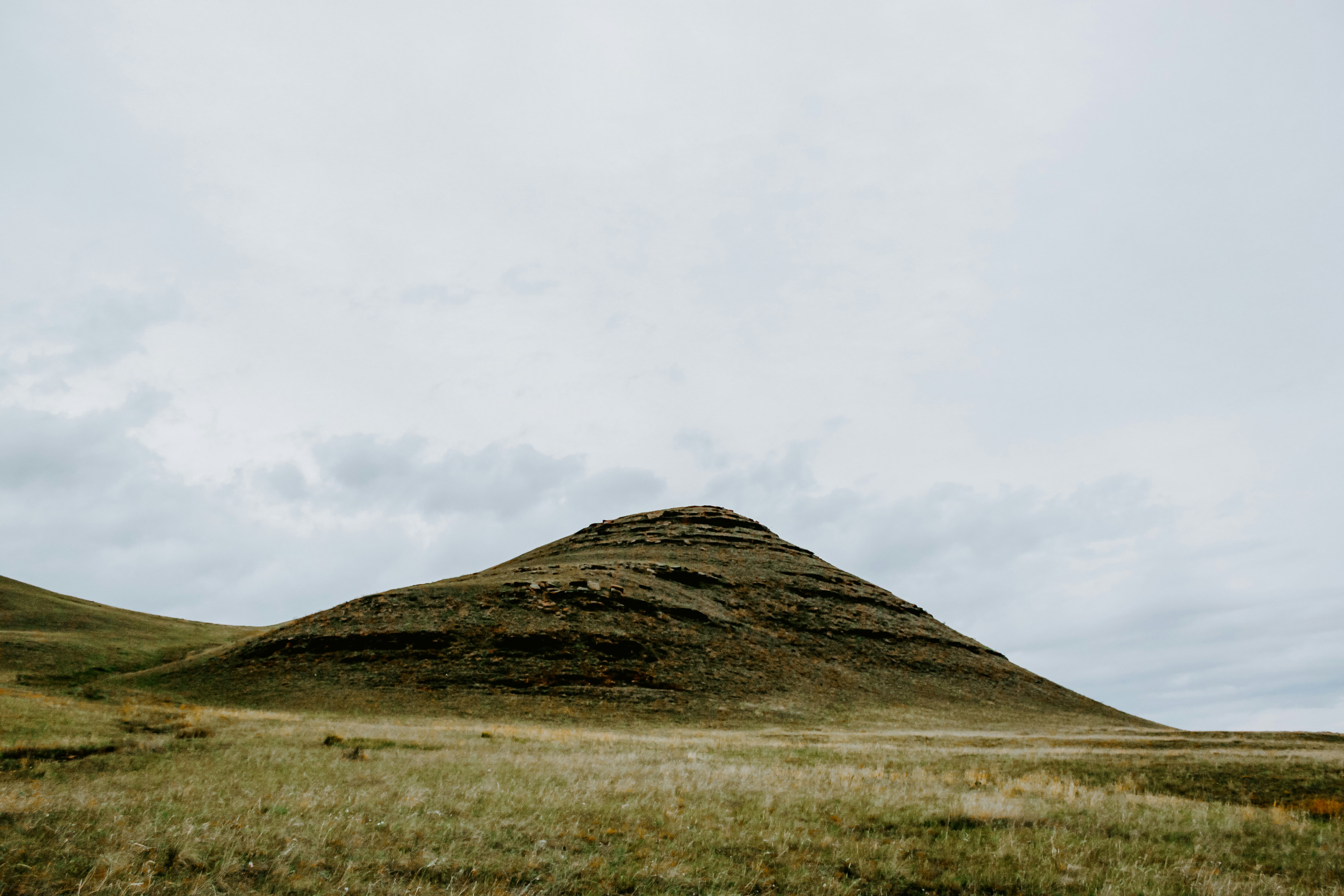 green grass field and mountain under white sky during daytime