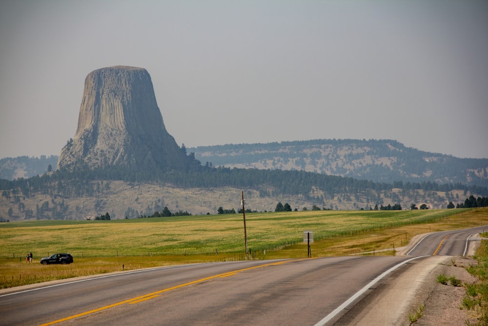 gray asphalt road near green grass field during daytime