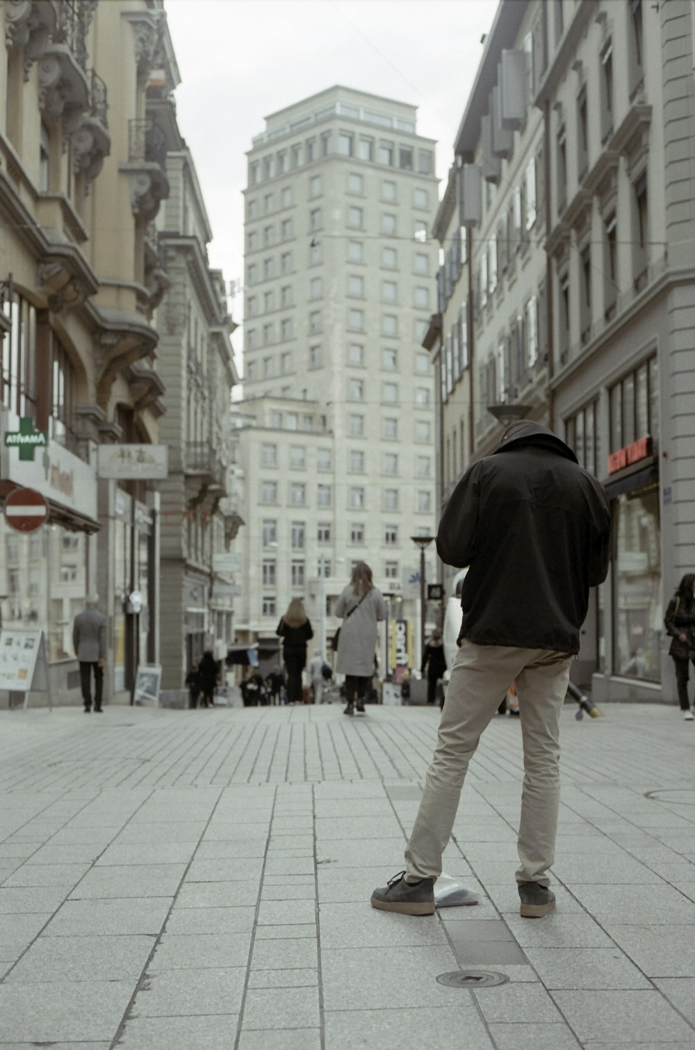 homme en sweat à capuche noir et pantalon gris marchant sur le trottoir pendant la journée