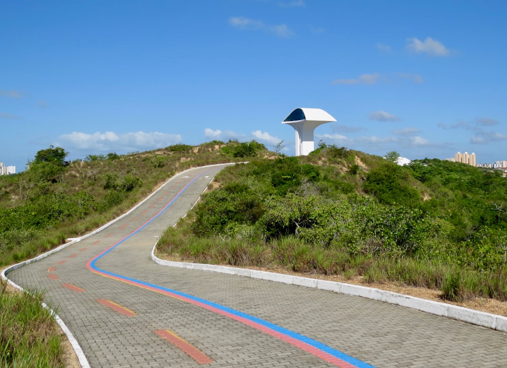 gray concrete road between green grass field under blue sky during daytime