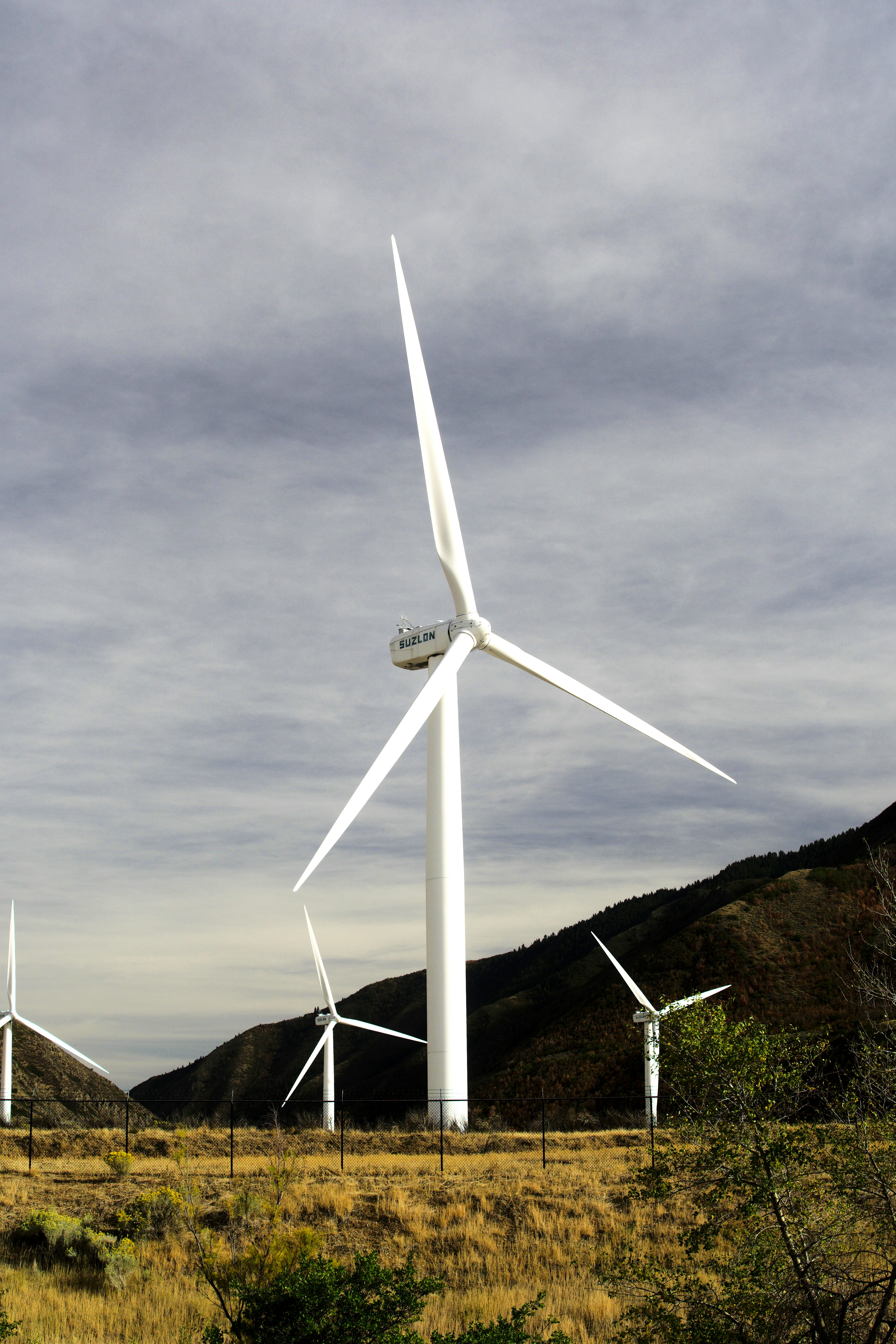 white wind turbine on hill under gray cloudy sky