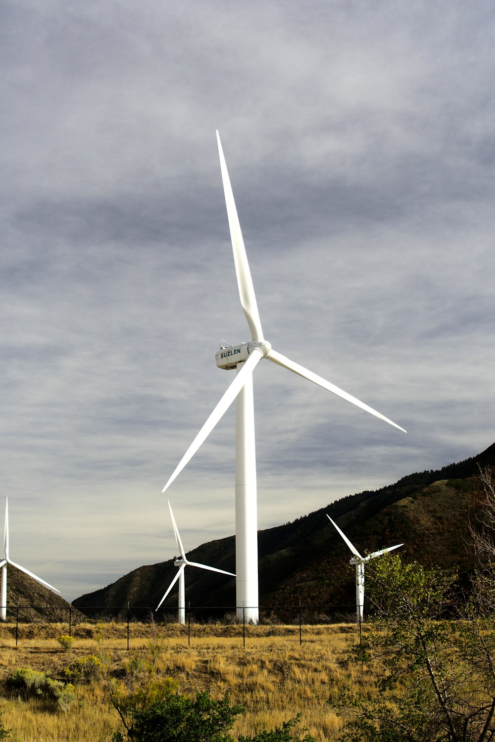 Éolienne blanche sur une colline sous un ciel nuageux gris