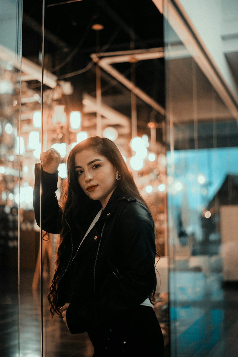 woman in black jacket standing near glass wall