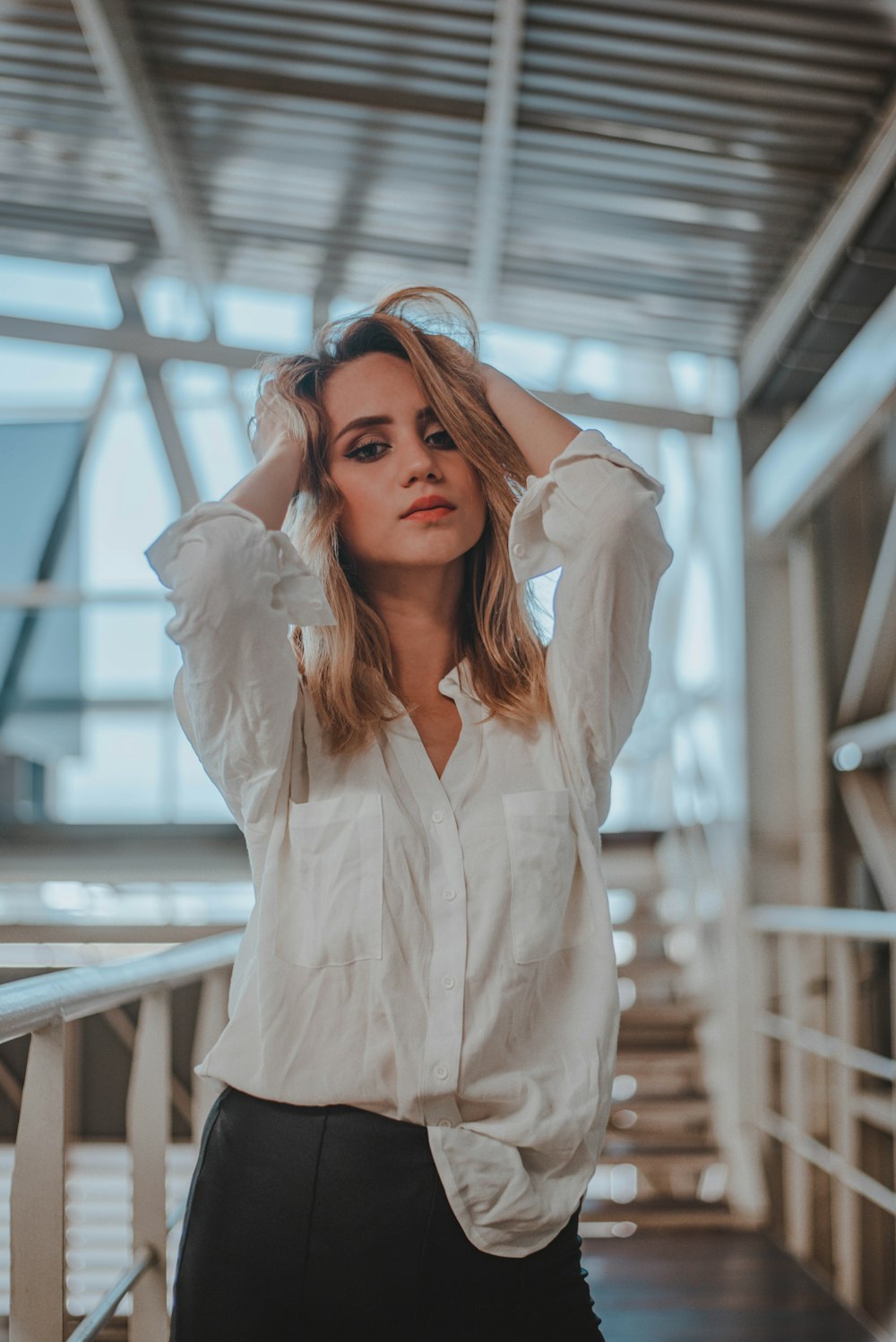 woman in white dress shirt standing near white metal railings during daytime