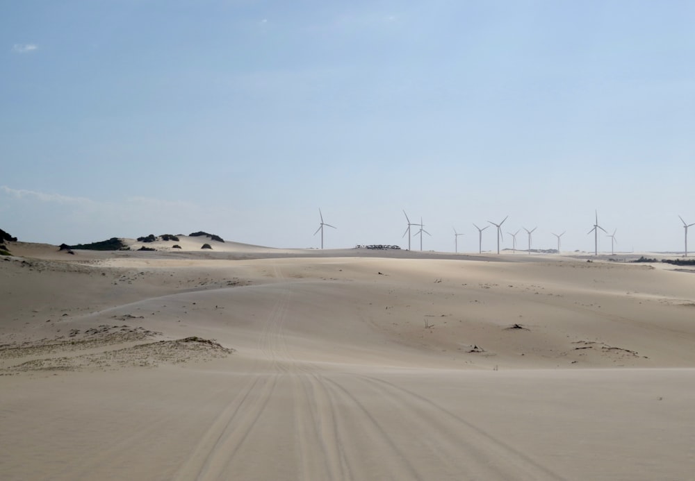 turbinas eólicas na areia marrom sob o céu azul durante o dia